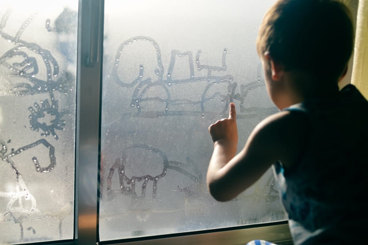 boy drawing on foggy window in Dallas