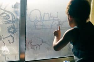 boy drawing on foggy window in Dallas